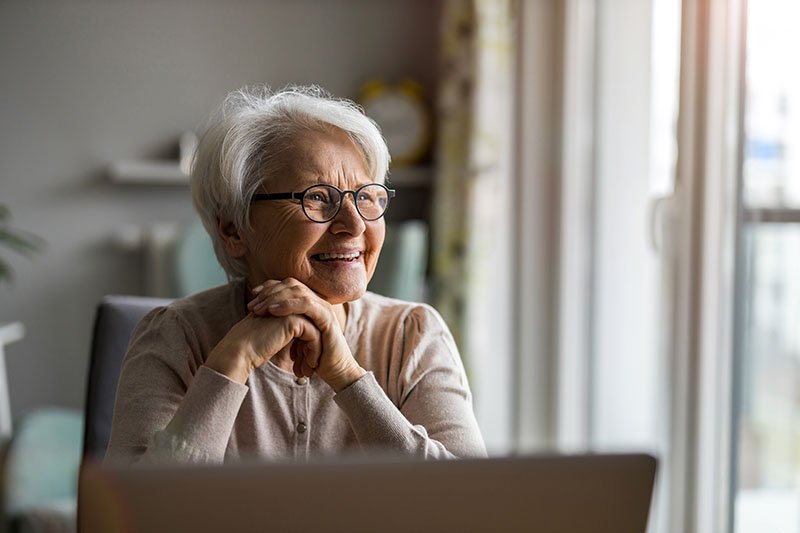A smiling older woman sitting at a table at home